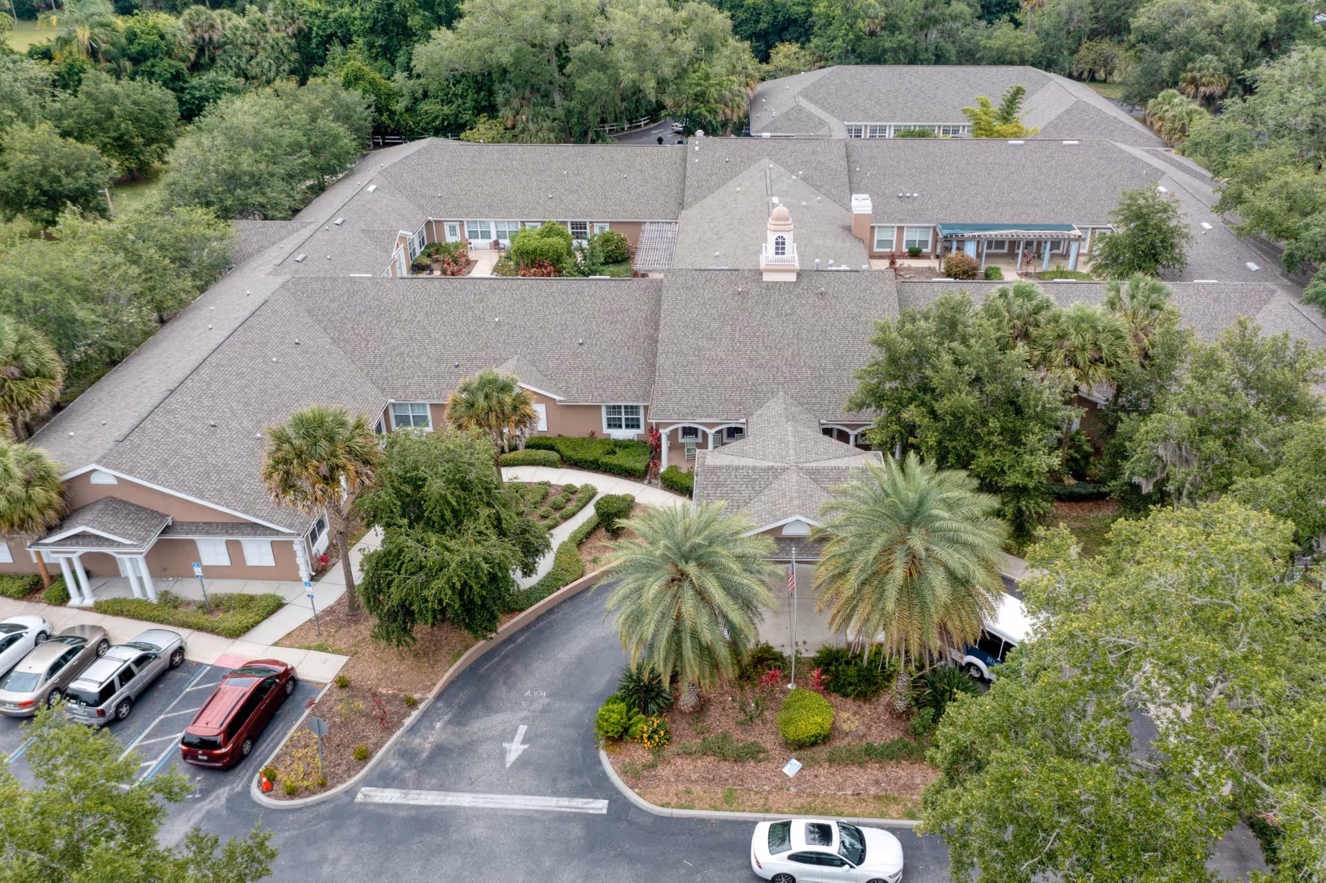 Aerial view of Addington Place of Titusville, showing a large single-story building surrounded by trees and landscaping, with a parking lot and several cars in front.