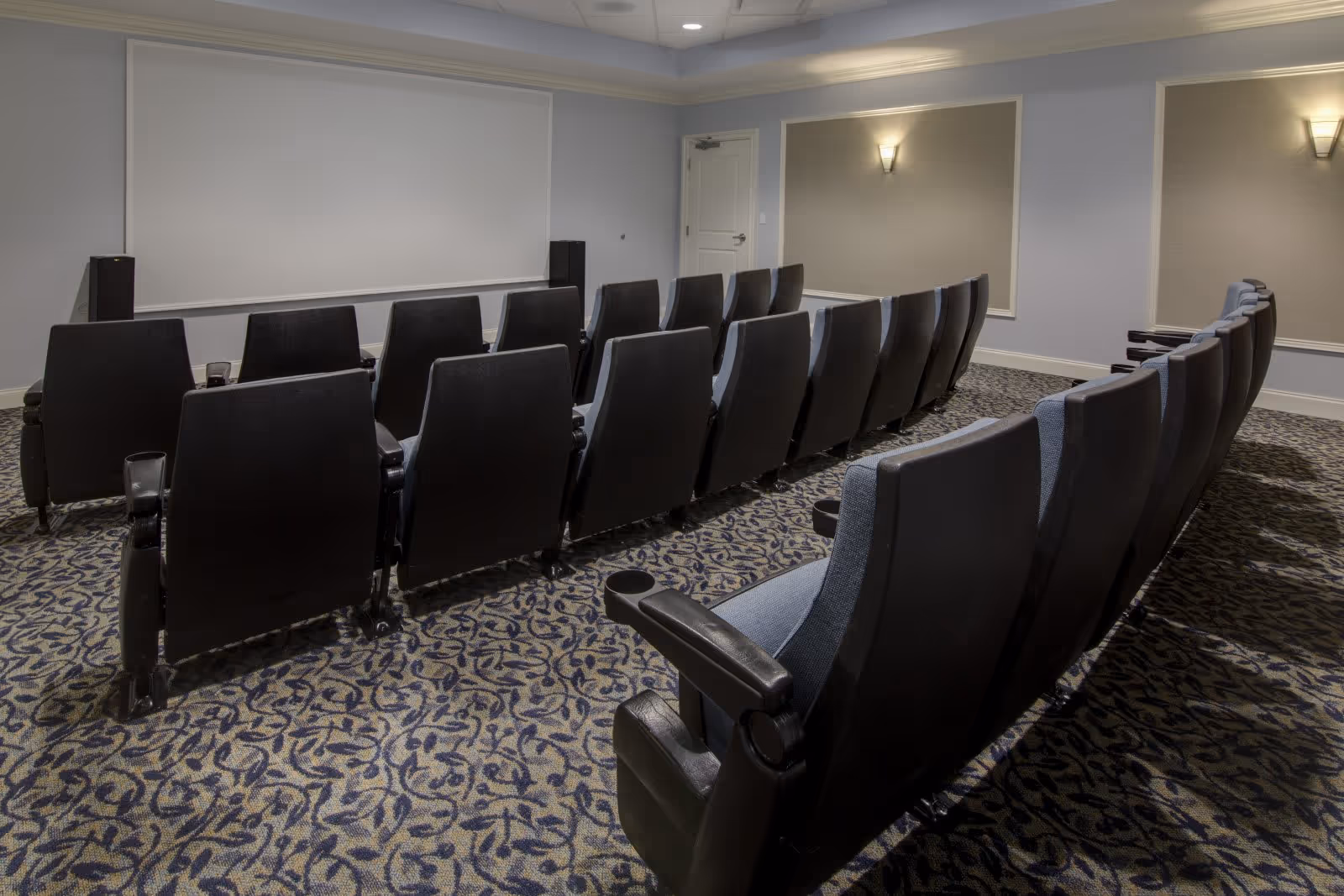 Small screening room with rows of theater-style seats facing a large projection screen.