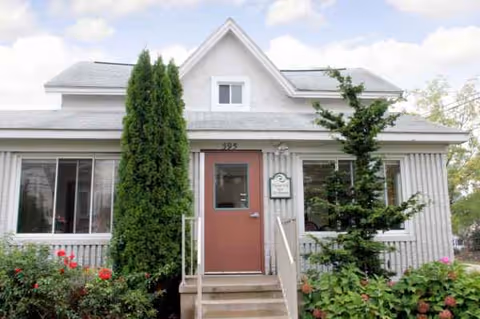 Front entrance of Medilodge of Plymouth, a senior living facility, with steps and greenery.
