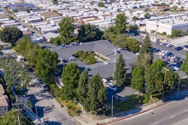 Aerial view of Claremont Care Center, a single-story U-shaped building with a central courtyard, surrounding trees and parking lots in a residential neighborhood.