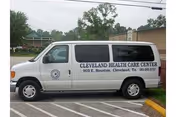 White Cleveland Health Care Center van parked in a lot beside a beige building.