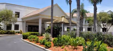 Front entrance of Volante of Dunedin with canopy, palm trees, and landscaped walkway.