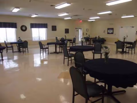 Empty senior living dining hall with round tables and chairs in a spacious room.