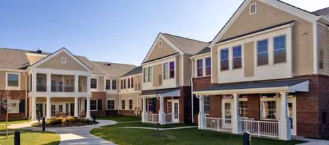 Exterior view of Elmcroft of Halcyon showing connected buildings and a grassy courtyard.