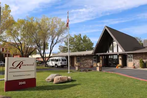 Exterior view of Rosewood Rehabilitation Center with sign, flagpole, and entrance.