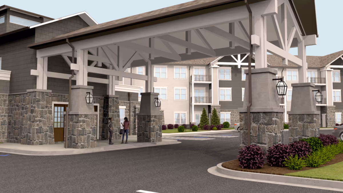 Entrance to a senior living facility with a stone pillar porte-cochere and landscaping.