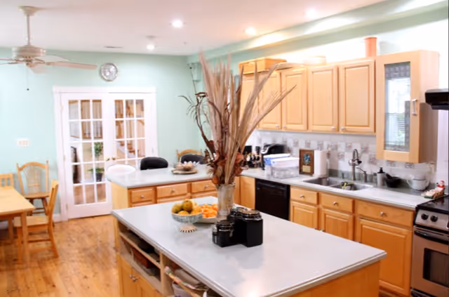 Bright open kitchen with a central island, light wood cabinets, a dining area and glass-paneled French doors.