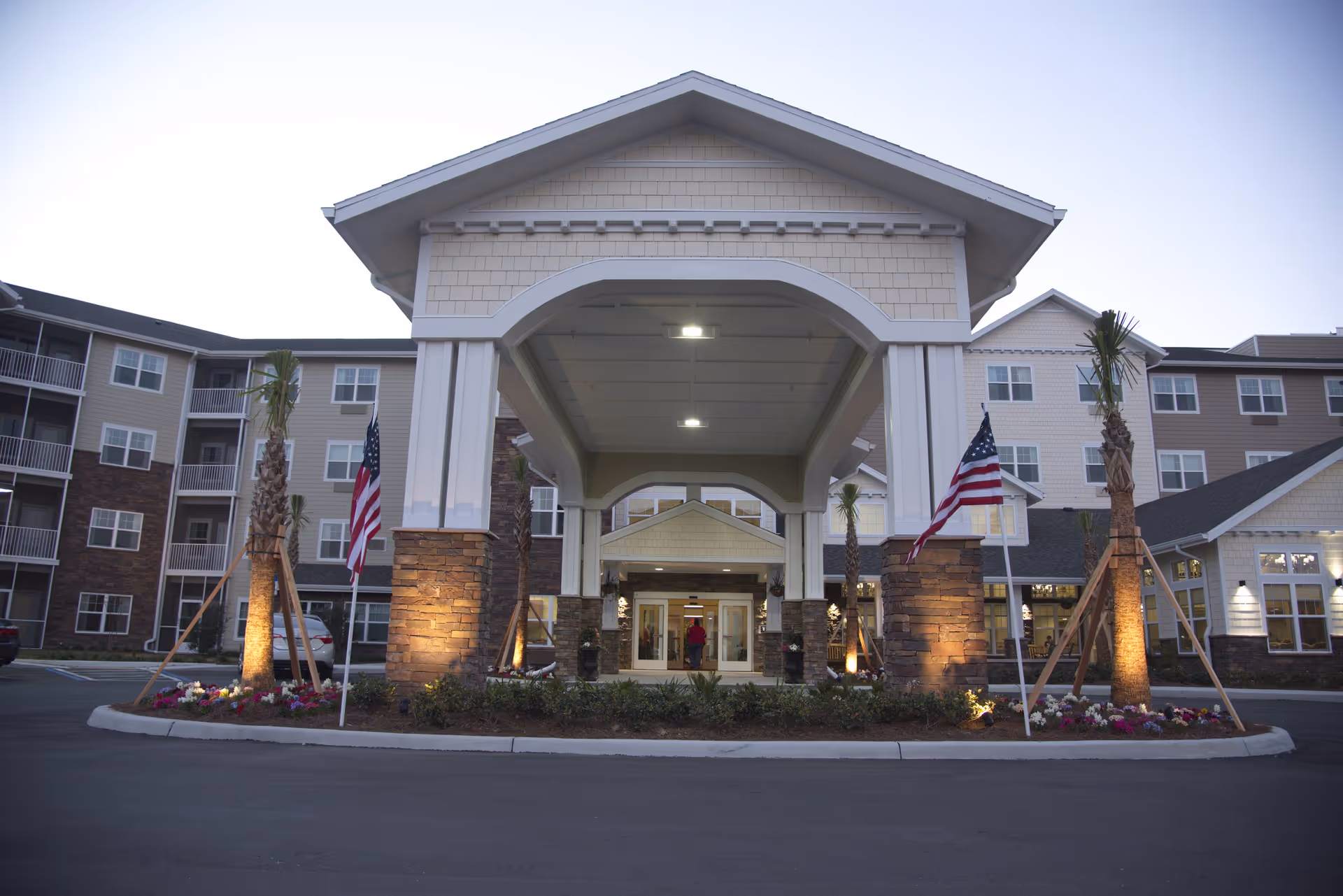 Exterior view of Cypress Springs Gracious Retirement Living facility with flags and landscaping.