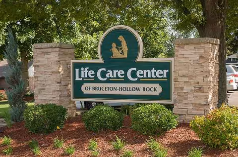 Exterior entrance sign for Life Care Center of Bruceton-Hollow Rock with stone pillars.