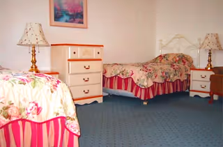 Two twin beds with floral bedspreads, matching nightstands and lamps in a softly decorated bedroom.