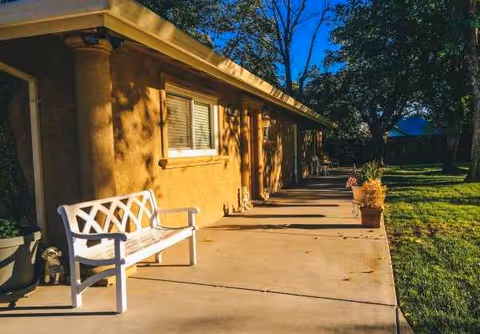 Exterior view of Garden Villa Elder Care with a bench along a walkway and planters.