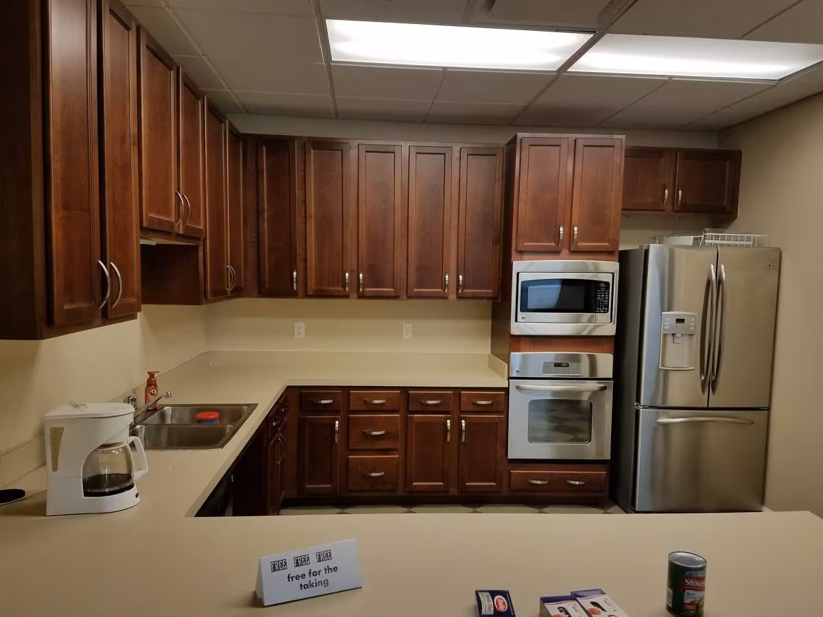 Kitchen with dark wood cabinets, stainless steel refrigerator and oven, a sink, and a coffee maker on the counter.