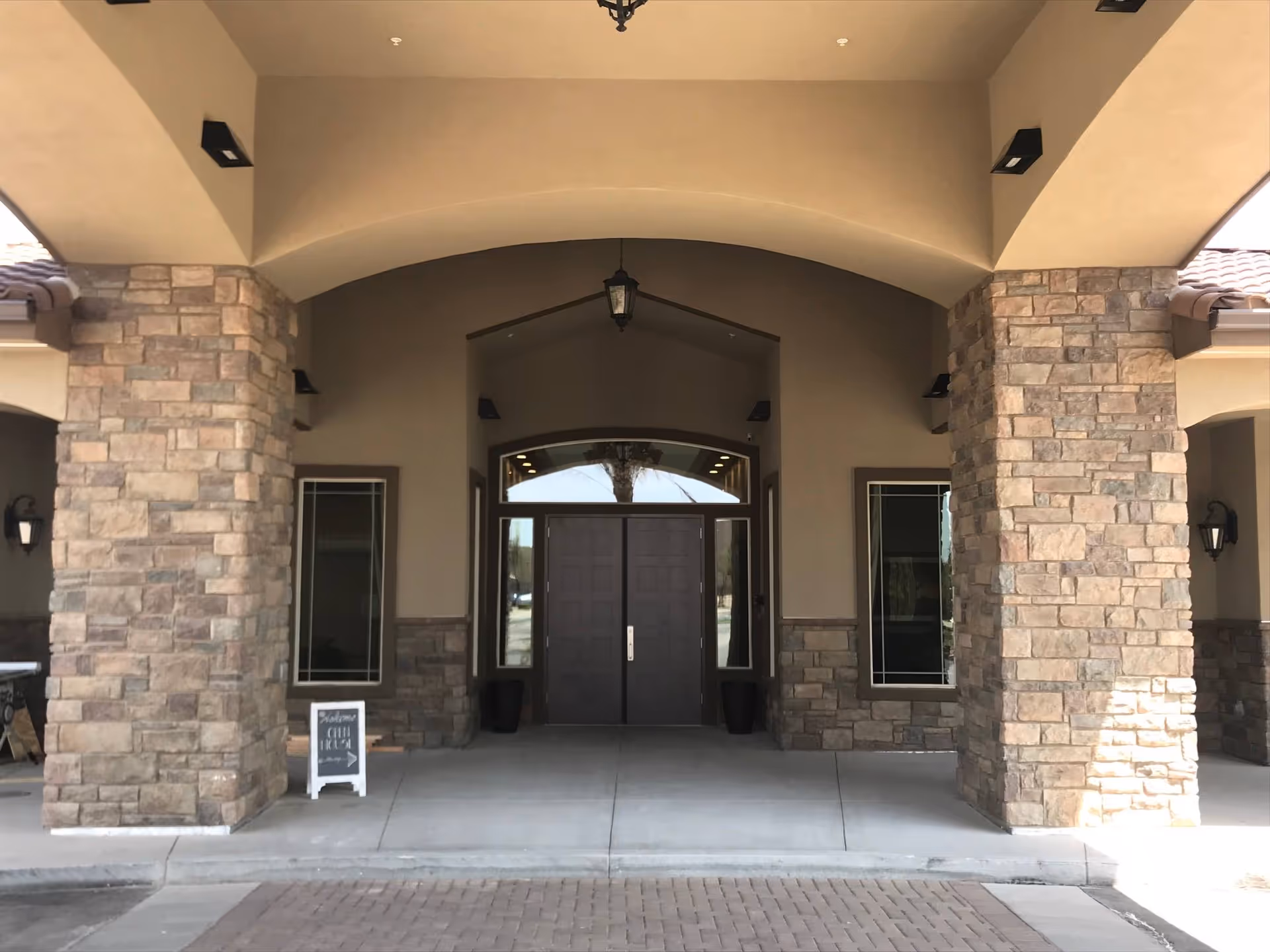 Stone-columned covered entrance with an arched portico and double doors.