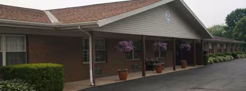 Exterior view of Colonial Manor Health Care Center with a covered entrance and potted plants