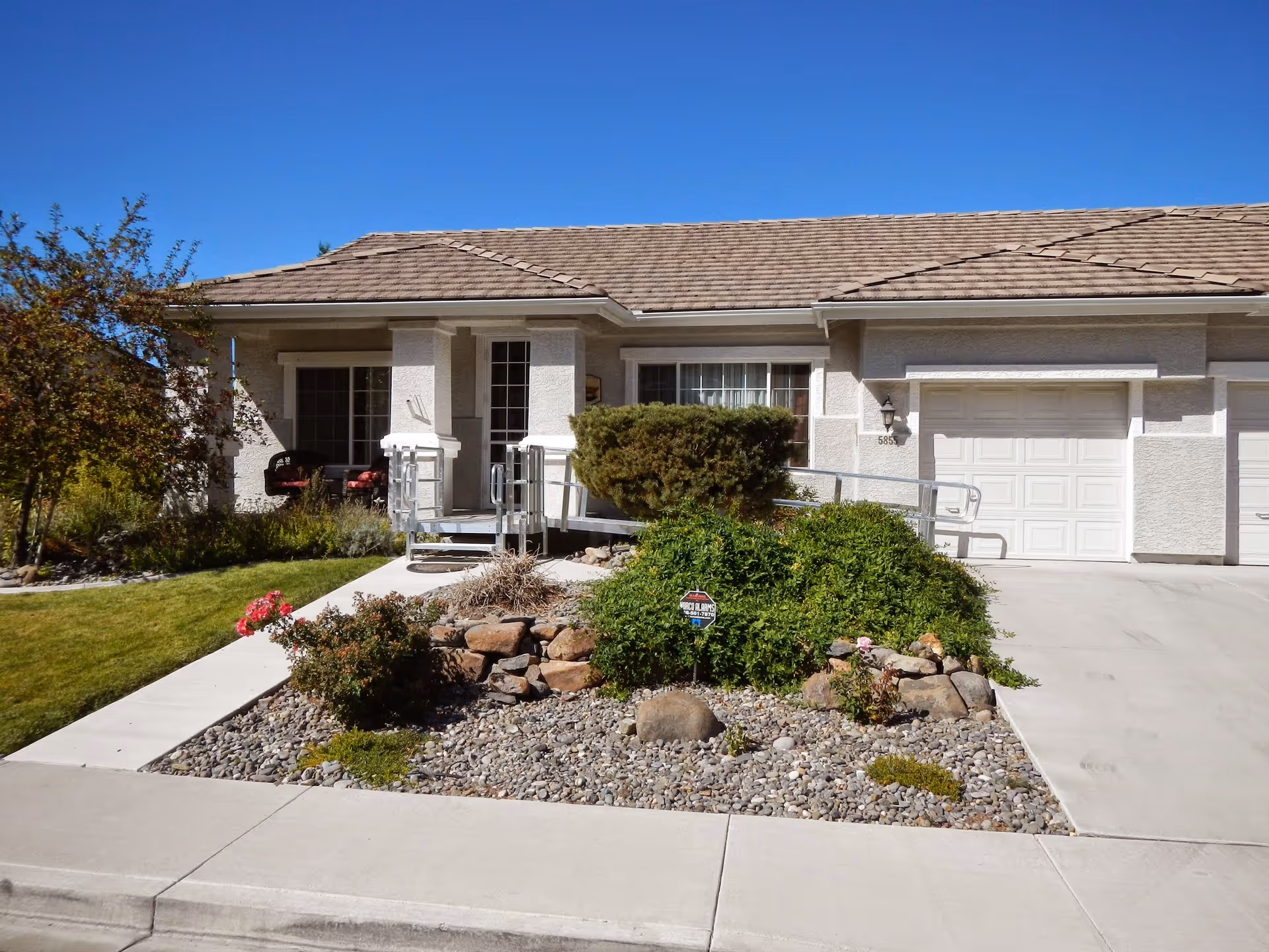Single-story senior living facility exterior with a ramp and landscaped front yard.