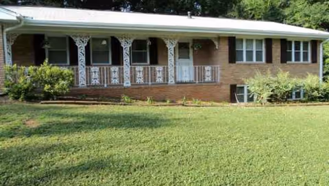 Single-story brick senior living facility with a white ornate porch and well-kept lawn.