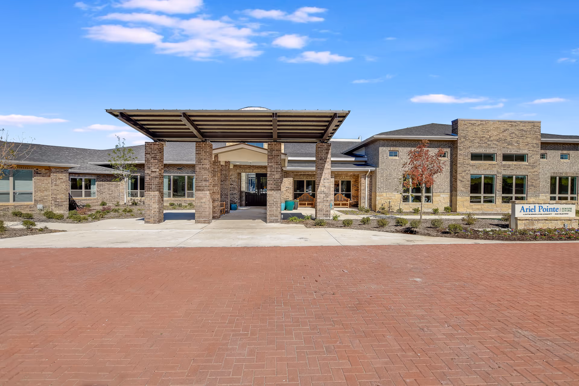 Exterior view of Ariel Pointe of Sachse Senior Living with a brick entrance and canopy.