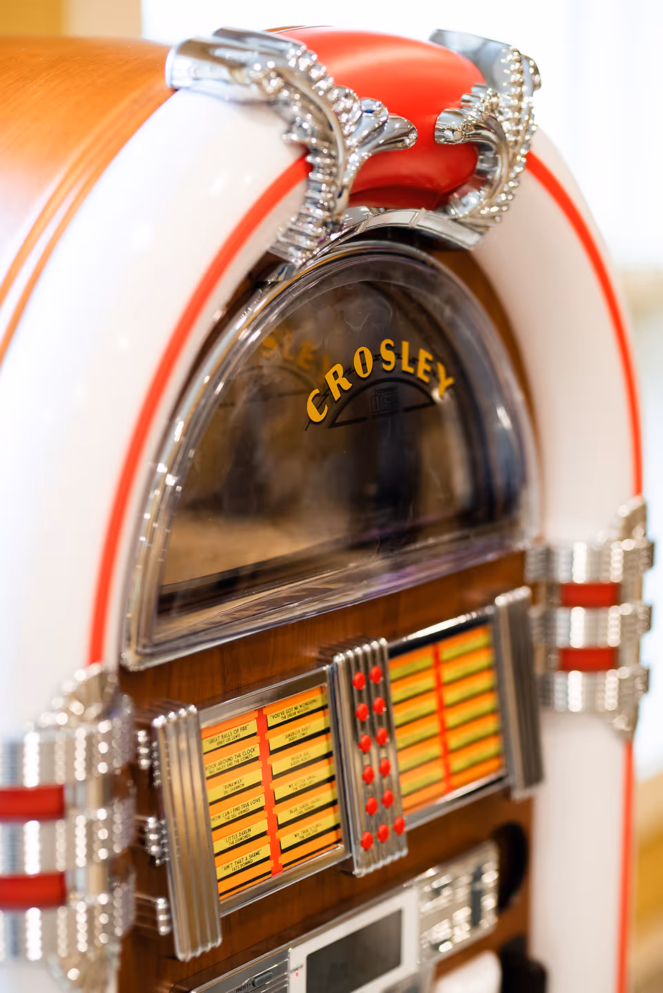 Close-up view of a vintage Crosley jukebox with red, white, and chrome detailing, featuring song selection buttons and a display window.