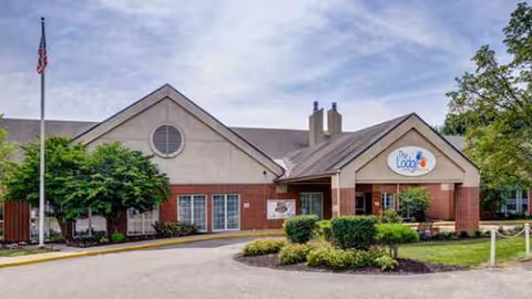 Exterior view of The Lodge Care Center showing the entrance and landscaped front yard.