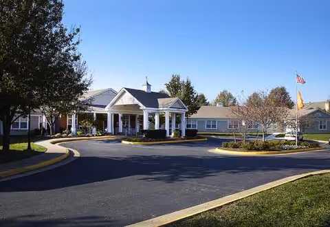 Exterior view of Sunrise at Huntcliff Summit I senior living facility with circular driveway and flagpole.