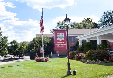 Exterior view of Emerson Health and Rehabilitation Center with lawn, banner, flag, and lamp.