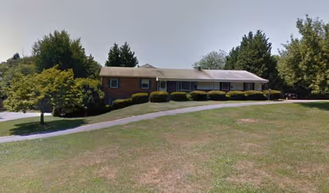 A single-story brick senior living facility is visible with manicured lawn and surrounding trees.