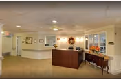 Well-lit reception lobby with a wooden front desk, seasonal wreath and floral decorations, and seating area.