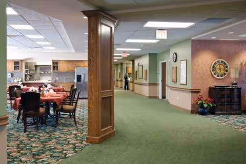 Interior common area of an assisted living facility with dining tables and a hallway.