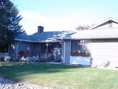A single-story blue house with a front porch and well-kept lawn.