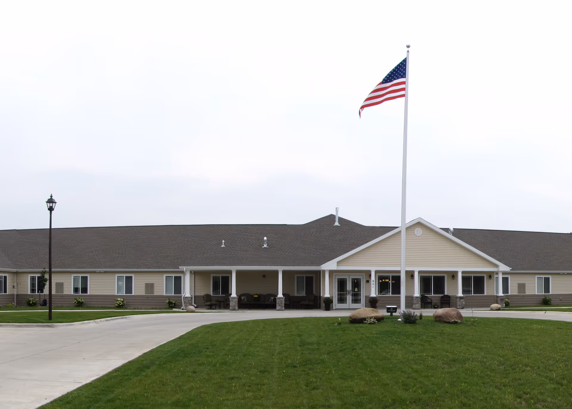 Exterior view of Emery Place senior living facility with a flag and landscaped lawn.