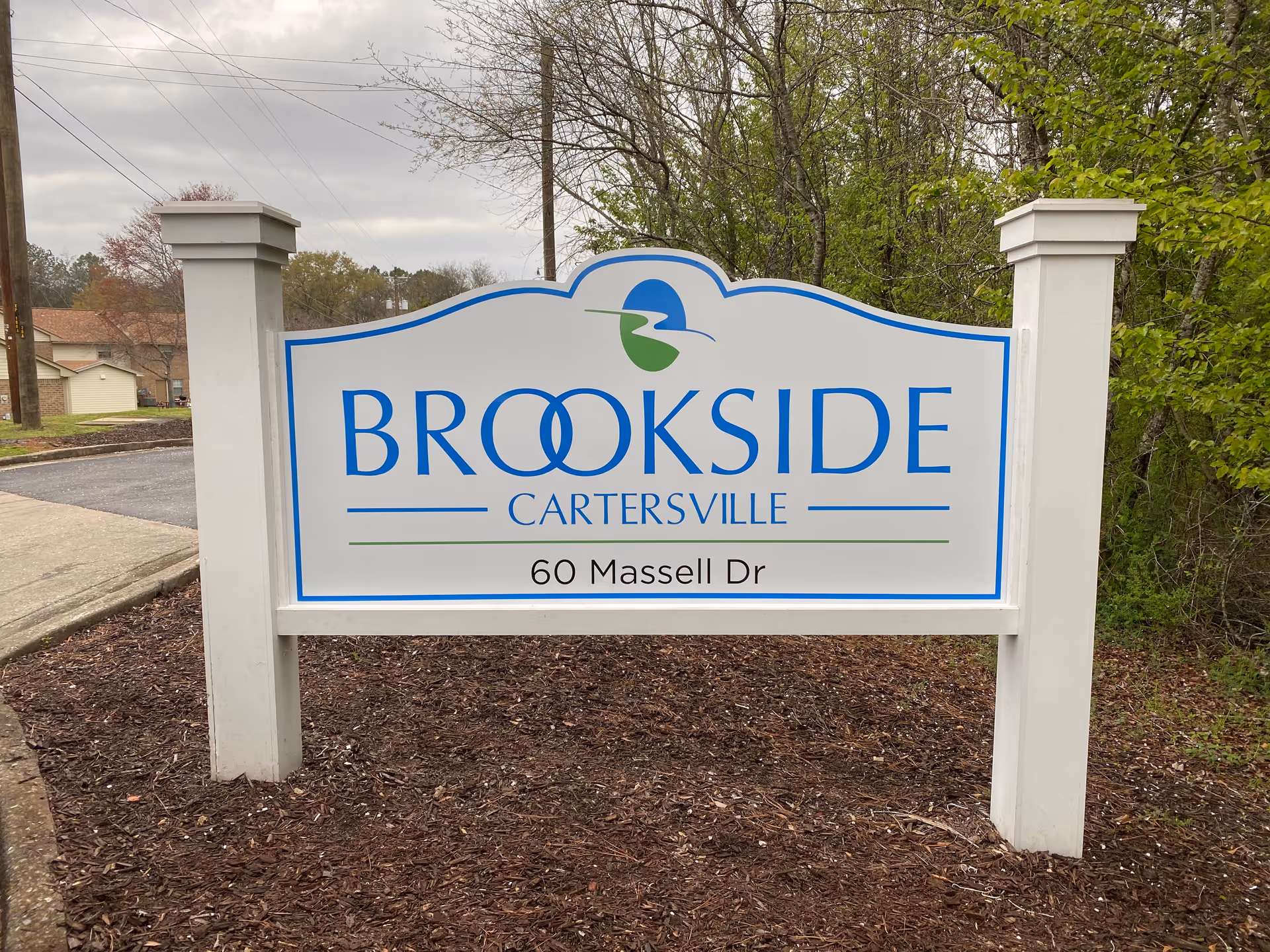 A freestanding outdoor sign reading "BROOKSIDE CARTERSVILLE" with the address "60 Massell Dr" mounted between two white posts.