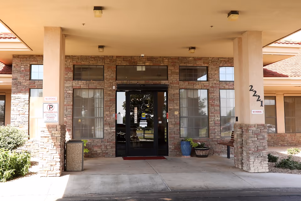Senior living facility entrance with stone facade, glass doors, and two pillars.