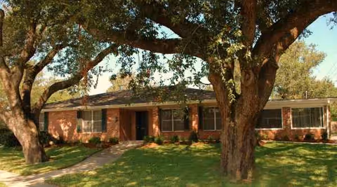 Brick, single-story Henican House facility with front entrance, manicured lawn, and large mature trees.
