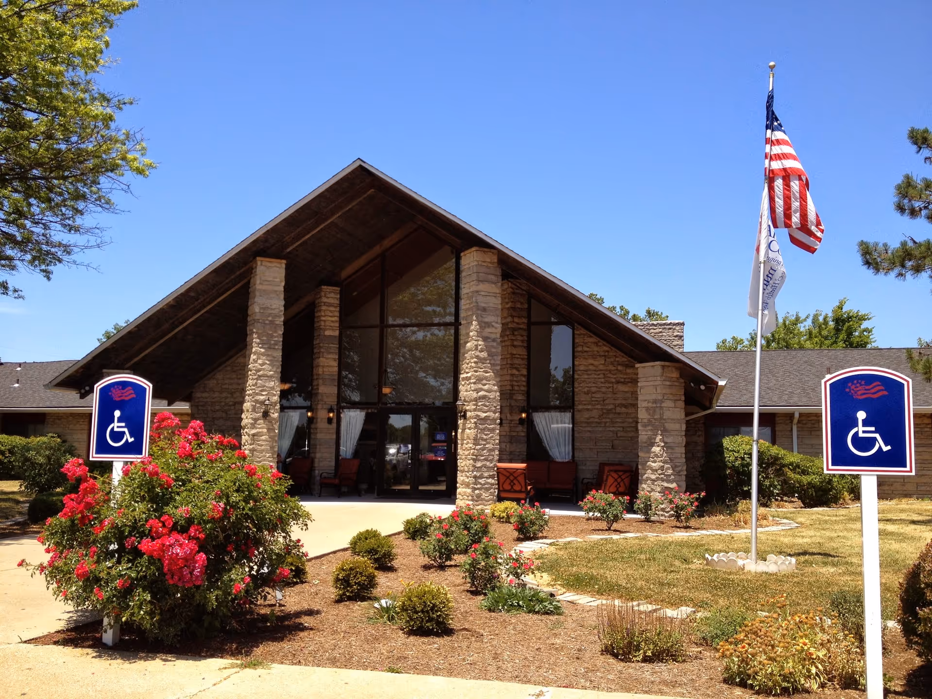 Front exterior of Westview Nursing and Rehabilitation Center showing a glass entrance, wheelchair-access signs, flagpole, and landscaped bushes.