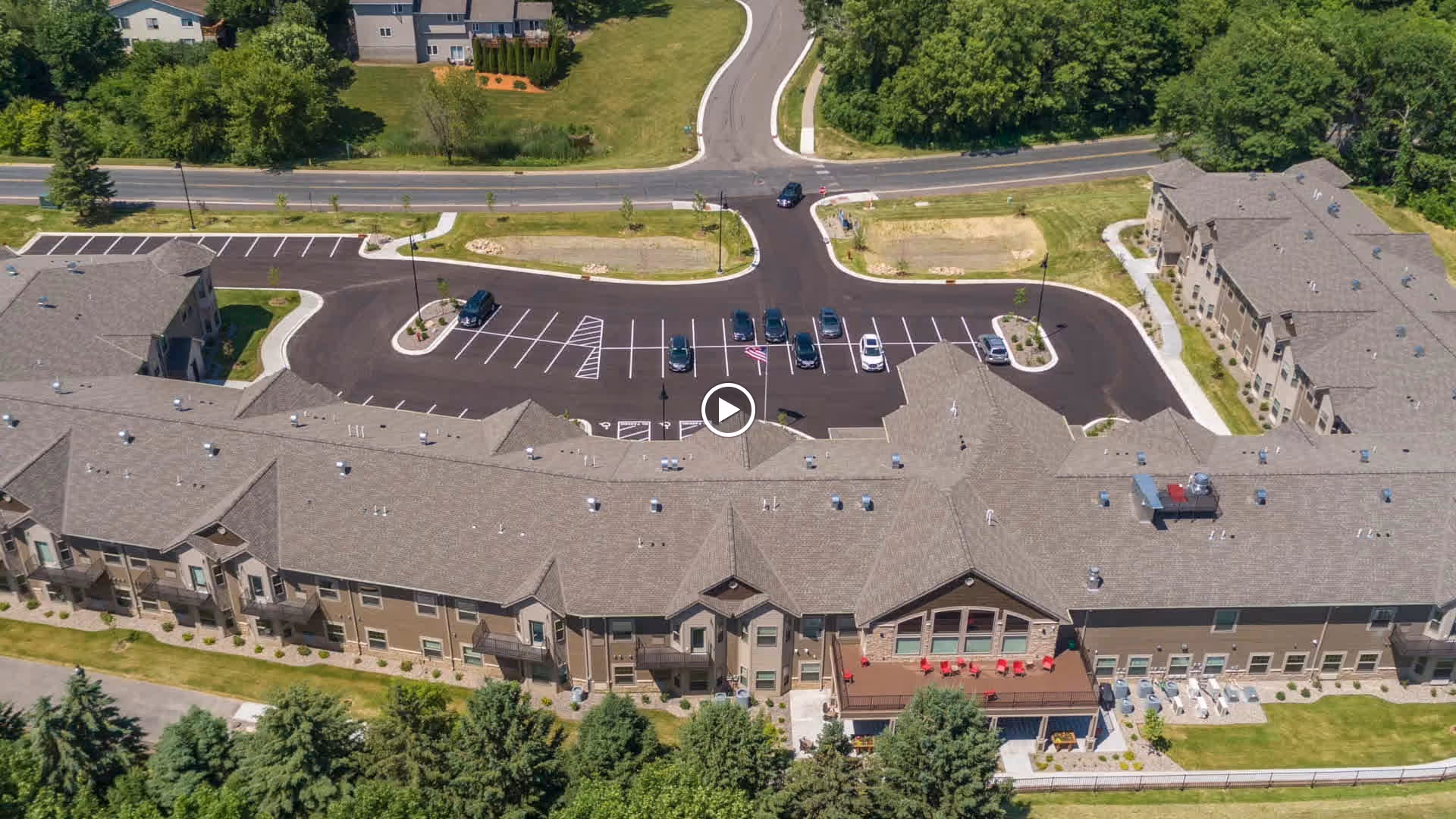 Aerial view of the Carver Ridge Senior Living complex showing a long multi-wing building, parking lot, and surrounding lawns and trees.