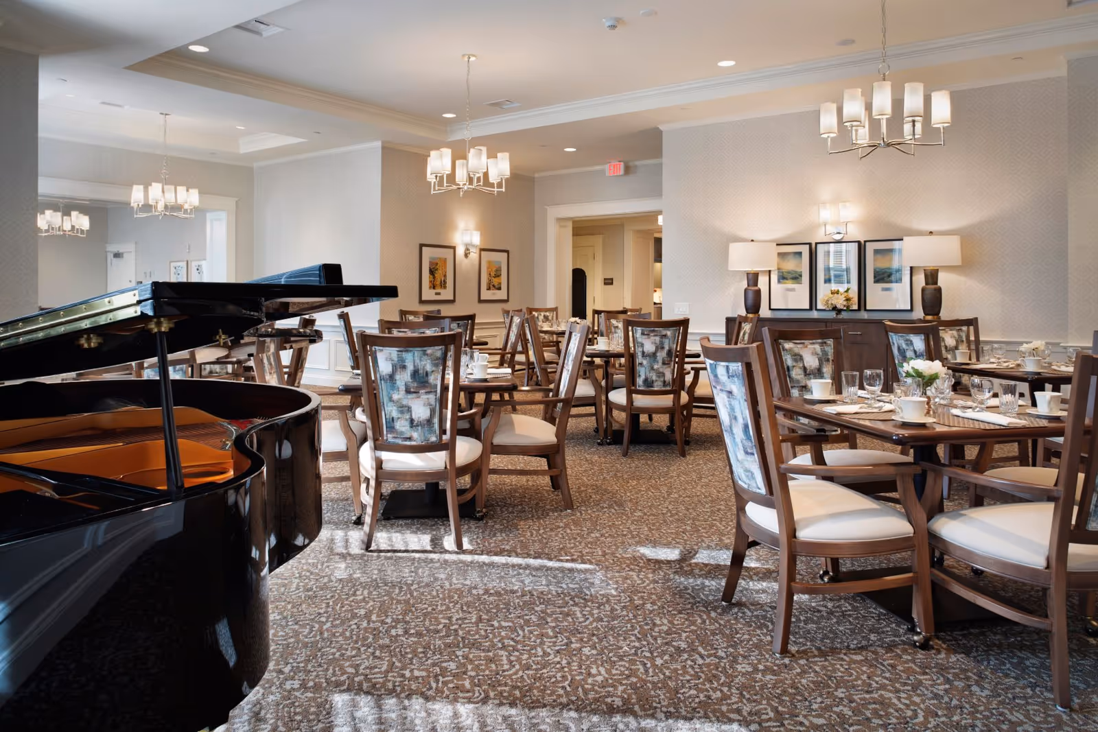 Elegant dining room with multiple set tables, chandeliers, and a grand piano in the foreground.