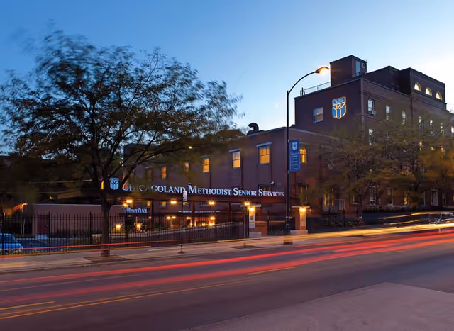 Exterior view of a brick senior services building at dusk along a city street.