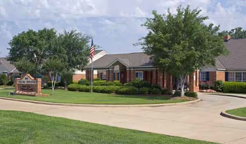 Exterior view of Azalea Estates of Monroe with circular driveway and landscaped grounds.
