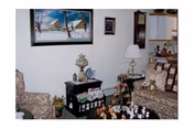 Cozy living room with patterned sofas, a coffee table covered in decorative figurines, a side table with a lamp, and framed artwork on the wall.