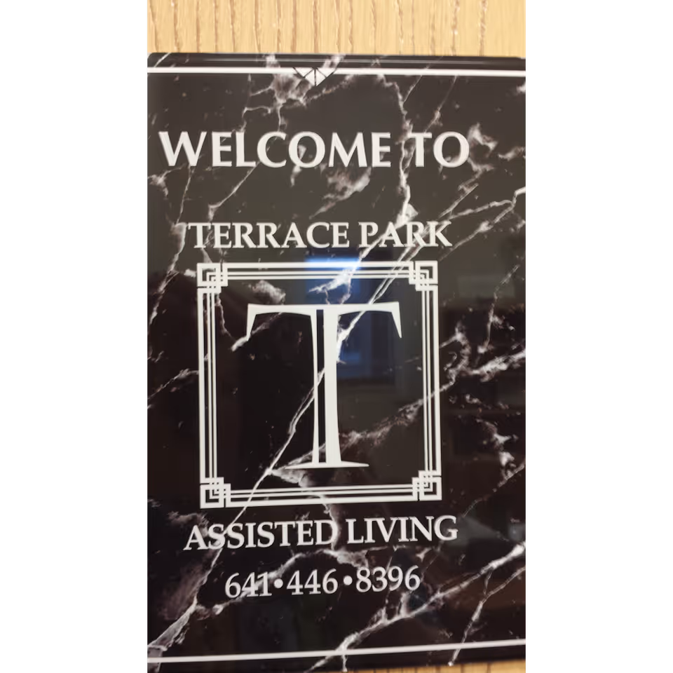 Marble-patterned sign that says "Welcome to Terrace Park Assisted Living" with a large "T" logo and a phone number.