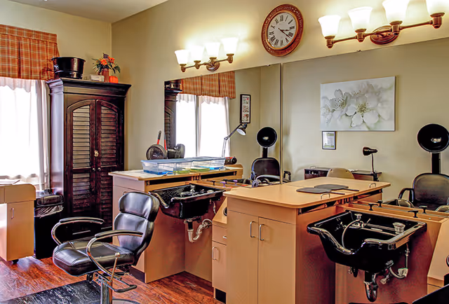 Interior salon area with styling chairs, shampoo sinks, mirrors, cabinetry, and wall lighting.
