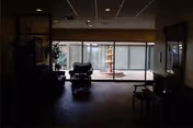 Dimly lit interior lounge with seating facing a large glass wall that looks out onto a courtyard fountain.