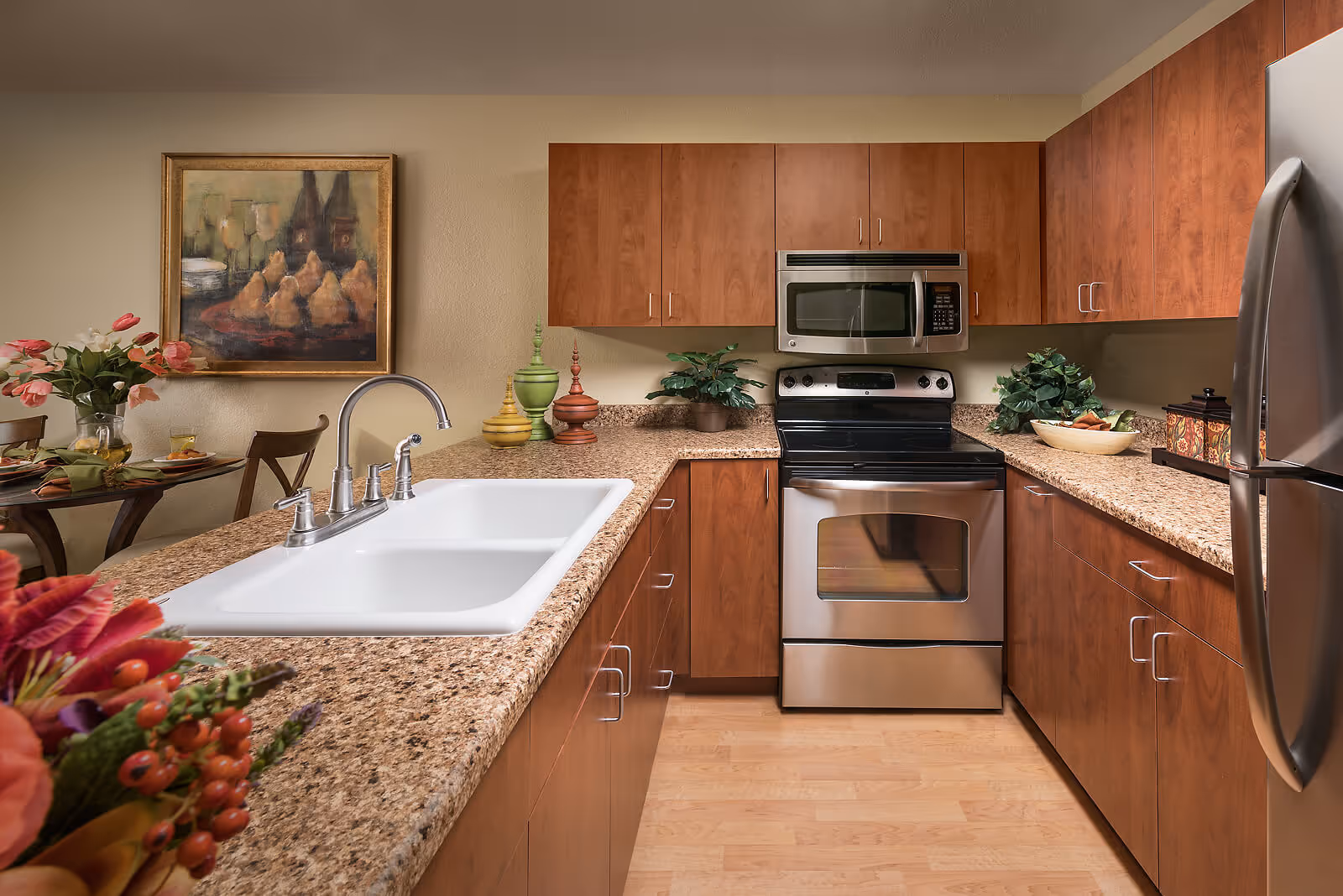 Well-appointed kitchen with granite counters, a white double sink, stainless steel stove and refrigerator, and wood cabinets.