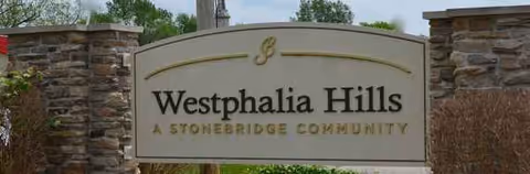 Exterior sign reads Westphalia Hills, A Stonebridge Community, flanked by stone pillars.