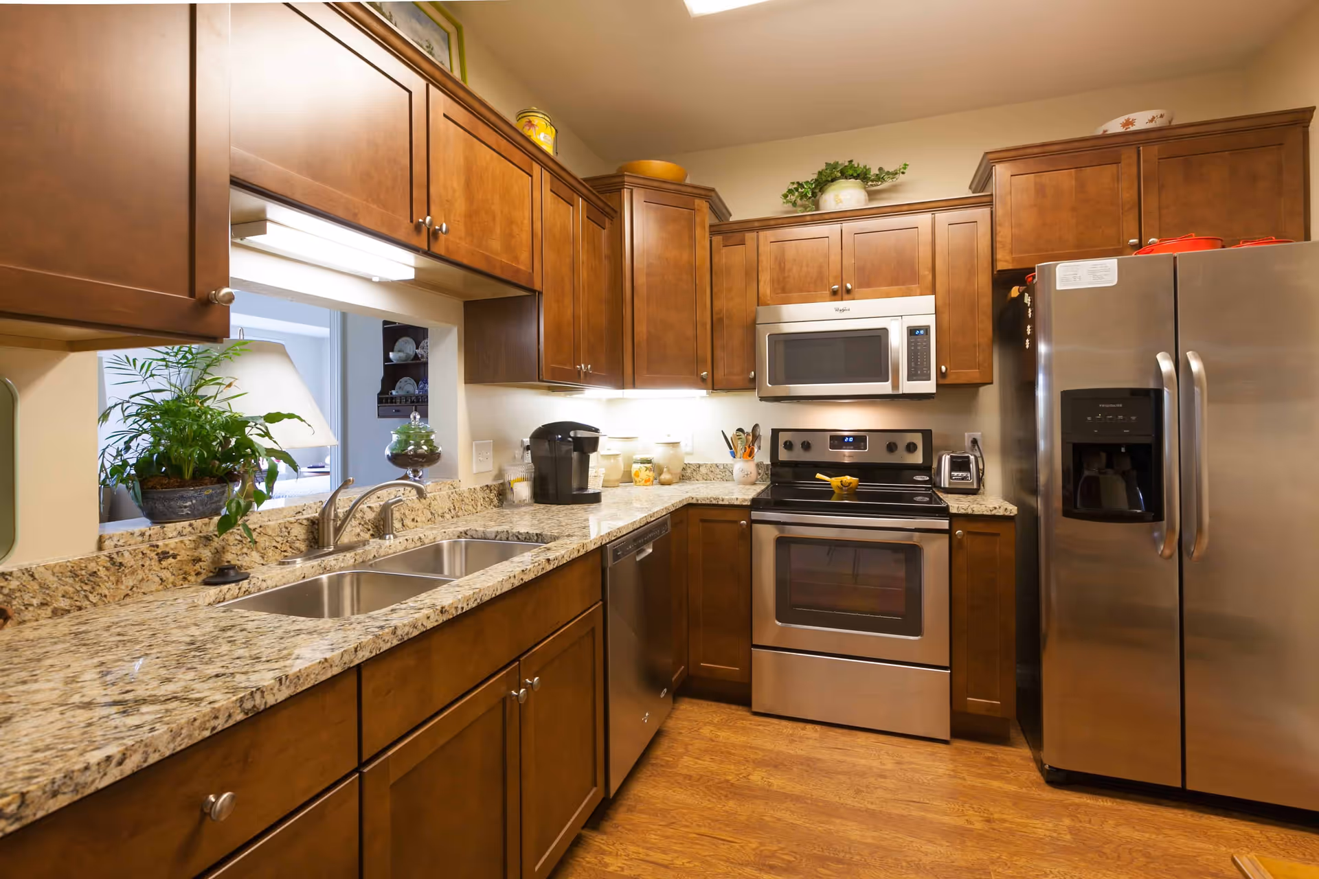 Modern kitchen with granite countertops, wooden cabinets, a double sink, and stainless steel appliances.
