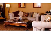 A cozy living room with two upholstered sofas, a wooden coffee table with decorative items, a floor lamp, and framed artwork on the wall.