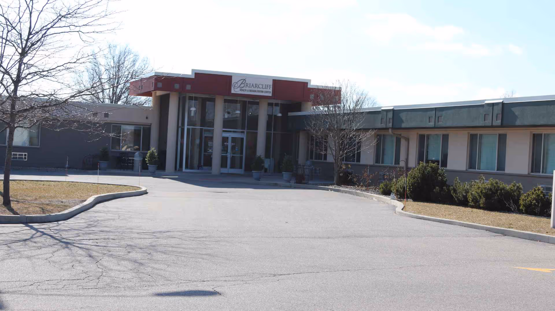 Entrance of the Briarcliff Health & Rehabilitation building with a driveway, columns, and landscaped grounds.