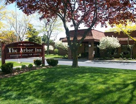 Front exterior of Arbor Inn assisted living facility with a sign and landscaped lawn.