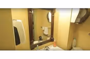 Bathroom sink and mirror with a hand towel, liquid soap, and a paper towel dispenser.