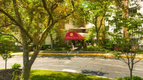Exterior view of Mayfair Village Retirement Center entrance with a red canopy.